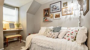A cozy bedroom with a bed, a desk with a chair, and a window with curtains. - Pool House w/ Outdoor Bar, Game Room & Movie Room (Irving)