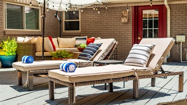 A deck with two lounge chairs and a table, a sofa with cushions, and a red door in the background. - Pool House w/ Outdoor Bar, Game Room & Movie Room (Irving)