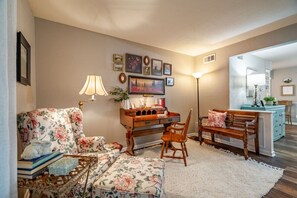 A cozy living room with a floral sofa, a wooden desk, and a bench. - Pool House w/ Outdoor Bar, Game Room & Movie Room (Irving)