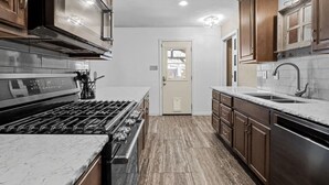 A kitchen with a stove, sink, and wooden cabinets. - Tropical Pool w/ Tiki Bar, Fire Pit, Swing (Richardson)