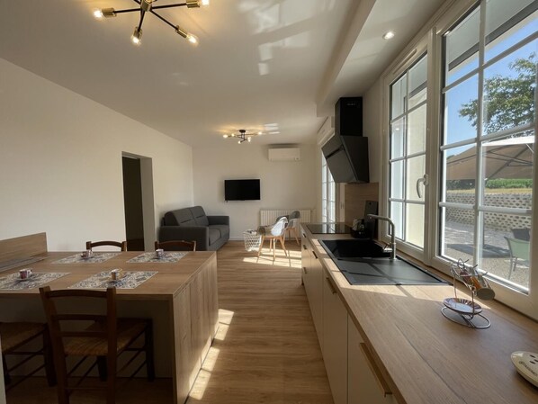 A modern kitchen with a large window, a dining area with a wooden table, and a built-in oven.