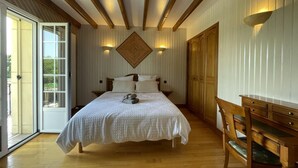 A bedroom with a bed, wooden furniture, and a sliding glass door to the outside. - SAMATHA - LASCLAVERIES (LASCLAVERIES)