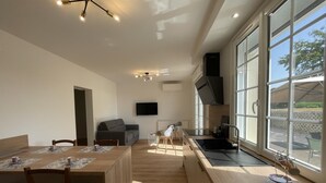 Una cocina moderna con un ventanal grande, un comedor con mesa de madera y un horno empotrado.