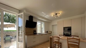 Una cocina moderna con una isla grande, un horno empotrado y un televisor montado sobre la isla.