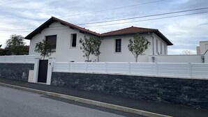 A modern two-story house with a white exterior, a tiled roof, and a stone wall foundation. - TOUTOU - ANGLET - Gîte (ANGLET)