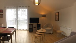A living room with a dining area, a TV, a chair, and a small table. - TOUTOU - ANGLET - Gîte (ANGLET)