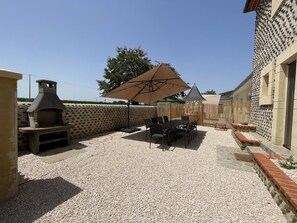An outdoor patio area with a barbecue grill, a table with chairs, and a large umbrella. - IRONDA - LASCLAVERIES (LASCLAVERIES)