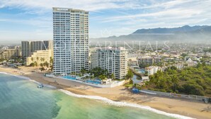 Un hotel costero con varios edificios altos, una playa y una vista despejada del océano.