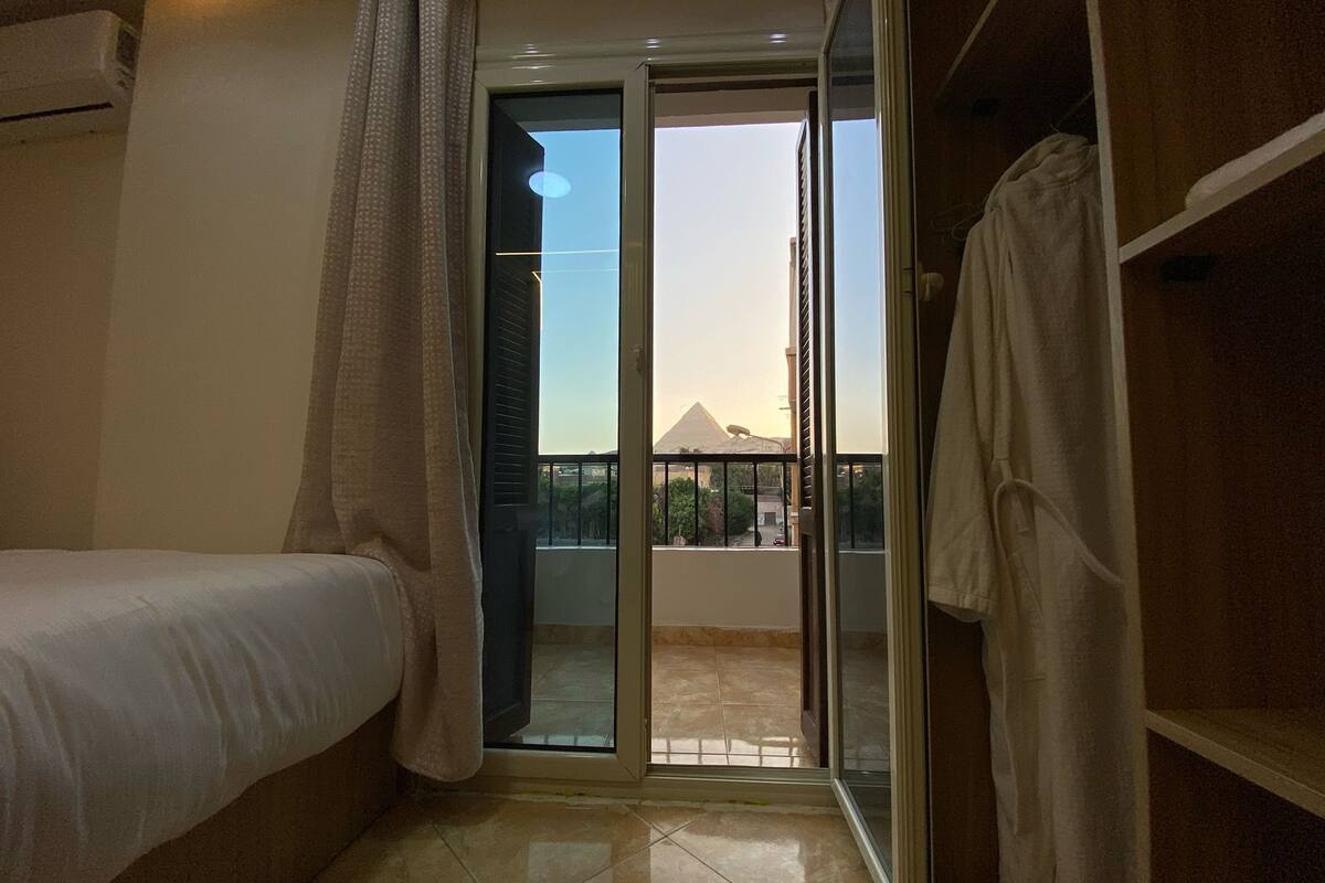 A bedroom with a bed, a sliding glass door leading to a balcony, and a wardrobe.
