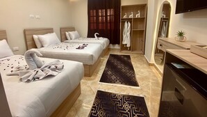 A hotel room with two beds, a vanity with a mirror, a television, and a wardrobe. - Isis pyramids view inn  (Giza)