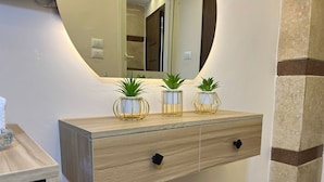 A wooden vanity with a mirror, three gold-framed plant pots, and a black handle drawer. - Isis pyramids view inn  (Giza)