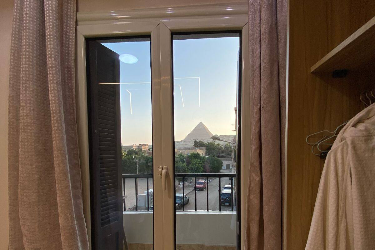 A hotel room with a sliding glass door leading to a balcony, a bed, a wooden wardrobe, and a towel rack.