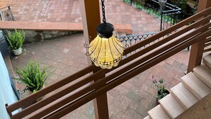 A staircase with a hanging light fixture, potted plants, and a brick-paved area outside. - Posada Conchita  (Tlalpujahua)