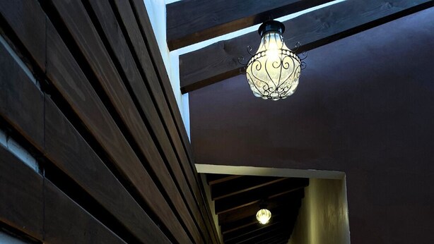 A narrow hallway with wooden slats on the left and a light fixture at the end. - Posada Conchita  (Tlalpujahua)