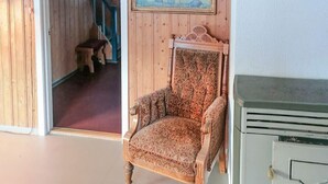 Una silla de madera con diseños elaborados, un banco de madera y un armario verde en una habitación con paredes de madera.
