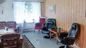 Una sala de estar con un sofá, sillones, una mesa de centro y una mesita con una planta.