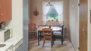Una cocina compacta con comedor, microondas, pileta y una ventana con cortinas.
