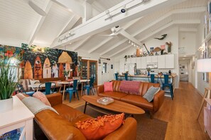 A spacious living area with a high ceiling, a dining area, and a kitchen. - Hygge By The Sea | Beachfront & Pet Friendly (Avon)