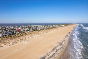 A coastal area with a sandy beach and a row of houses along the shoreline.