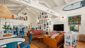 A spacious living area with a large sofa, a dining table, and a kitchen in the background. - Hygge By The Sea: Beachfront Retreat (Avon)