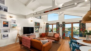 A spacious living area with a television, sofa, and dining table. - Hygge By The Sea: Beachfront Retreat (Avon)