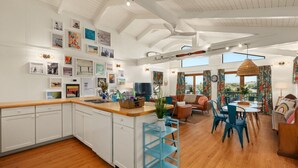 A spacious kitchen with a central island, a dining area with a round table, and a living room with a sofa and chairs. - Hygge By The Sea: Beachfront Retreat (Avon)