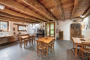 A rustic interior with wooden tables and chairs, a piano, and a stone wall. - Apartment 'Le Fratte' with Mountain View, Private Garden and Wi-Fi (Pertica Alta)