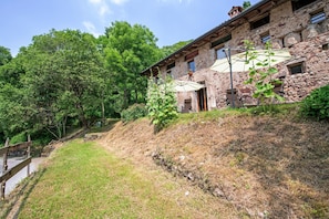 A stone building with a sloped roof, a paved path, and a wooden fence. - Apartment 'Le Fratte' with Mountain View, Private Garden and Wi-Fi (Pertica Alta)