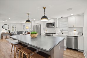 A modern kitchen with a large island, stainless steel appliances, and pendant lighting. - Inviting Escape Bursting w/ Elegance & Style (Lutherville)