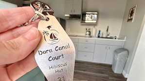 Une clé portant la gravure « Dora Canal Court Hibiscus Hut 31 », tenue dans une main.