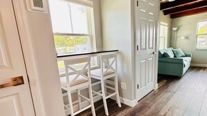 Une pièce avec un plancher en bois, des murs blancs, une porte blanche et une fenêtre.