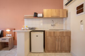 Een kleine keuken met een koelkast, een koffiezetapparaat, een broodrooster en een spoelbak.