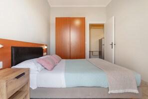 A bedroom with a bed, wooden wardrobe, bedside table, and a door leading to a bathroom. - Apartment '' with Mountain View, Wi-Fi and Air Conditioning (Zante)