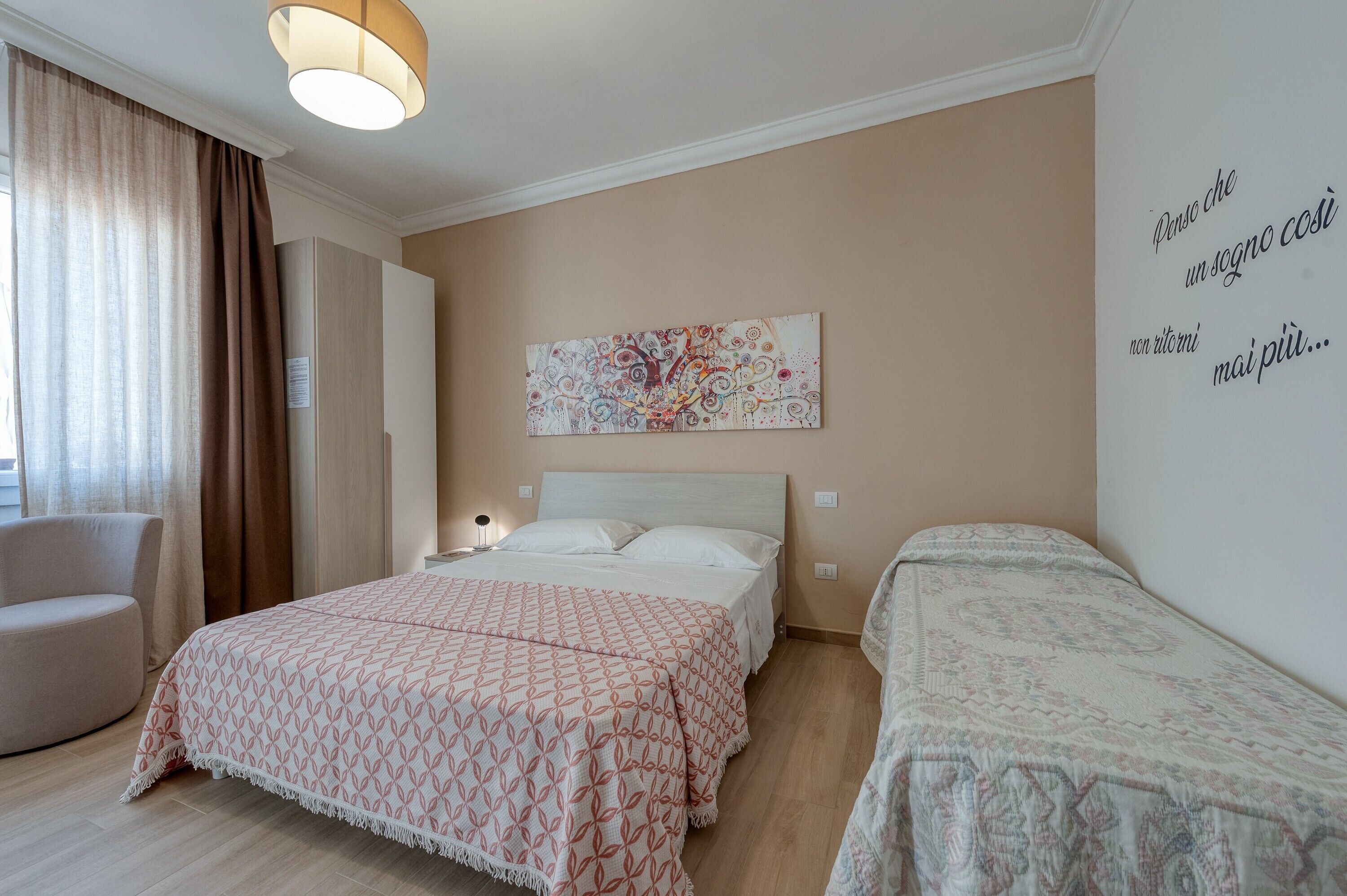 Una habitación de hotel con una cama, una silla, una mesita de noche, una obra de arte en la pared y un texto en la pared.