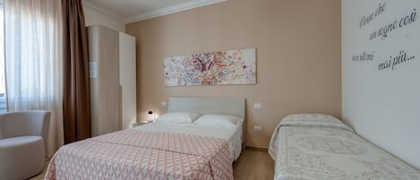 Una habitación de hotel con una cama, una silla, una mesita de noche, una obra de arte en la pared y un texto en la pared.