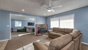A living room with a beige sectional sofa, a fireplace, and a ceiling fan.