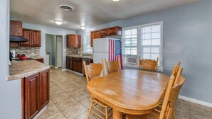 A spacious kitchen with wooden cabinets, a large island, and a dining area with a wooden table and chairs.