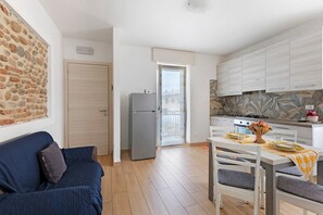 A compact living space with a kitchenette, a dining area, and a blue sofa.