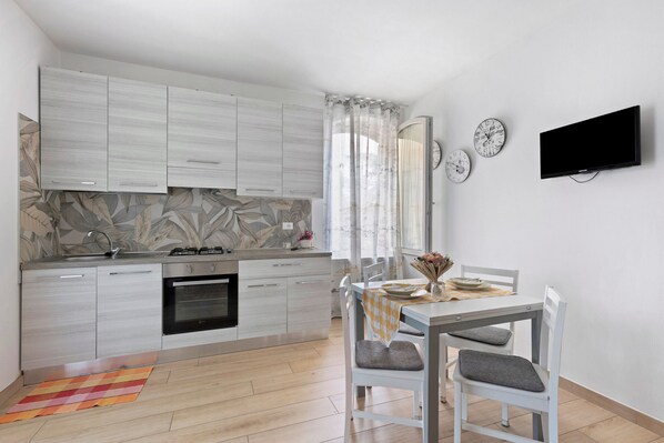 Una cocina moderna con armarios blancos, estufa a gas y comedor con mesa y sillas.
