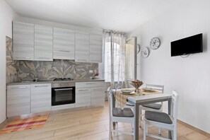 A modern kitchen with white cabinets, a gas stove, and a dining area with a table and chairs.