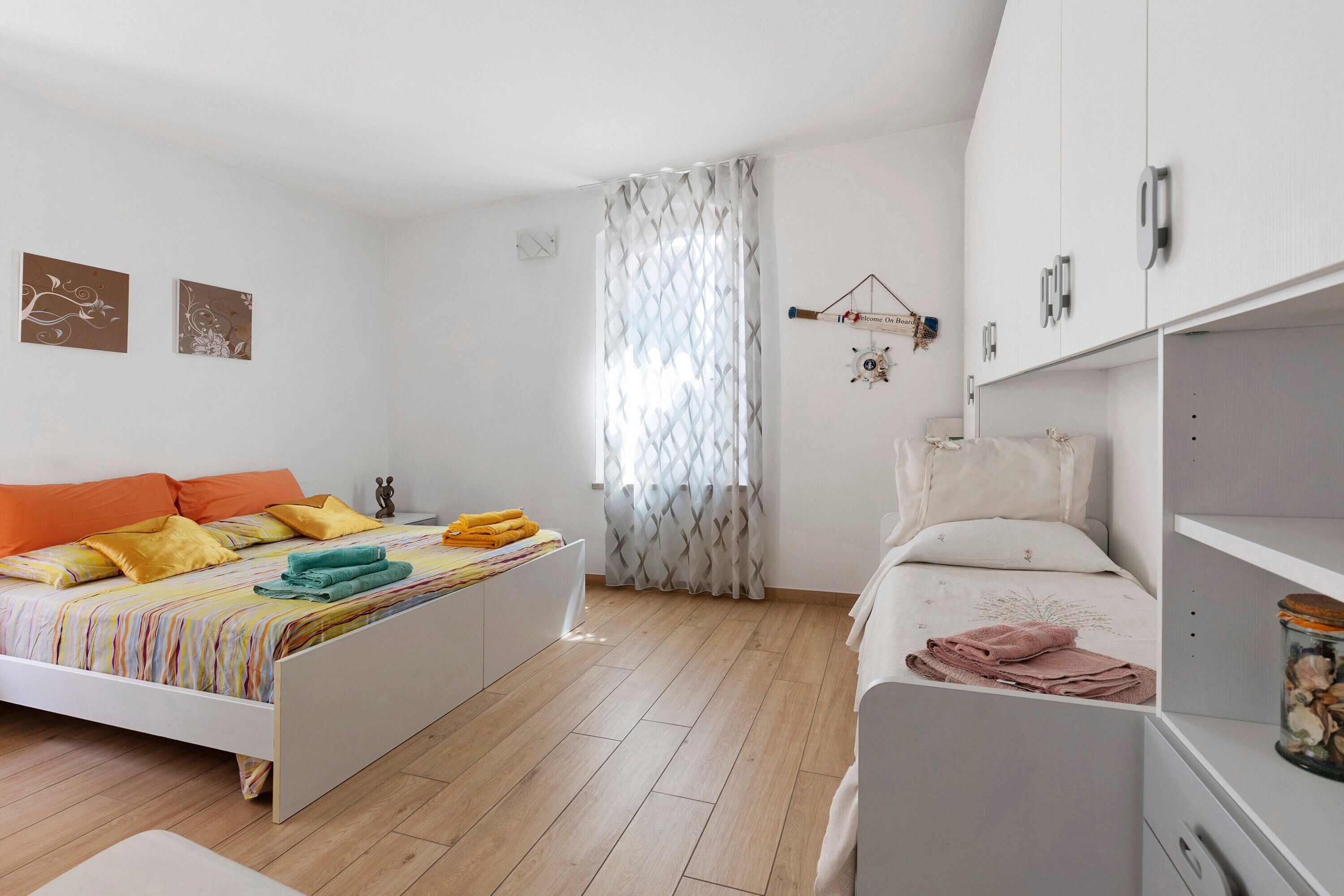 Ein Schlafzimmer mit einem Bett, einem Nachttisch, einem Kleiderschrank und einem Fenster mit Vorhängen.