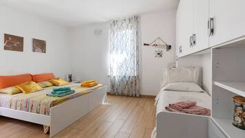 Ein Schlafzimmer mit einem Bett, einem Nachttisch, einem Kleiderschrank und einem Fenster mit Vorhängen.