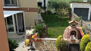 A patio with a stone wall, a small brick oven, and potted plants.