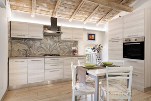 Een koelkast, een oven, een kookplaat, kookgerei, borden en bestek