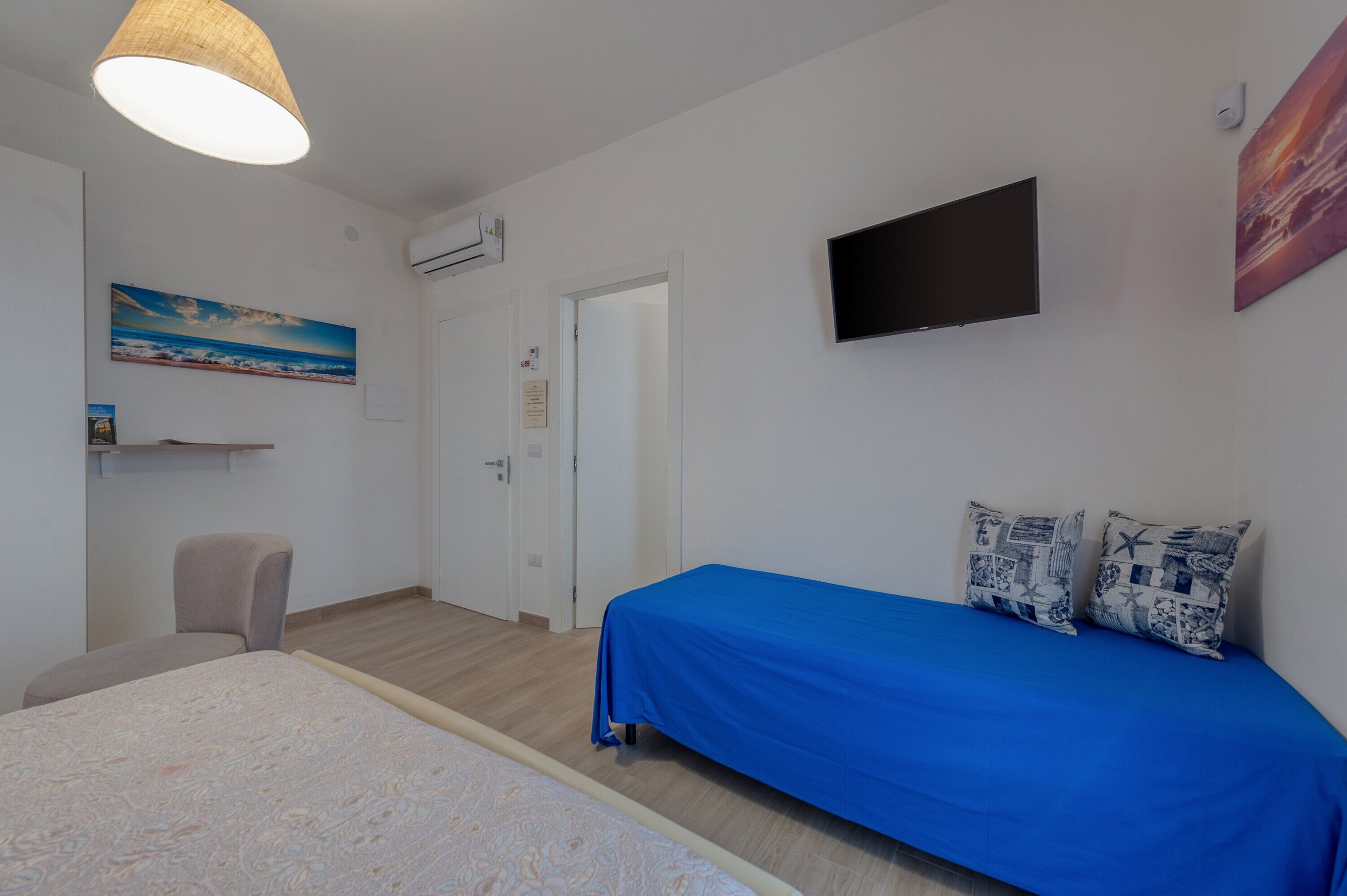 A bedroom with a bed, a chair, a TV, and a door.
