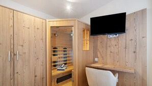 Un armario de madera con un televisor montado en la pared, una silla y una estantería empotrada.
