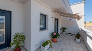 Un balcone con piante in vaso, una porta e una finestra.