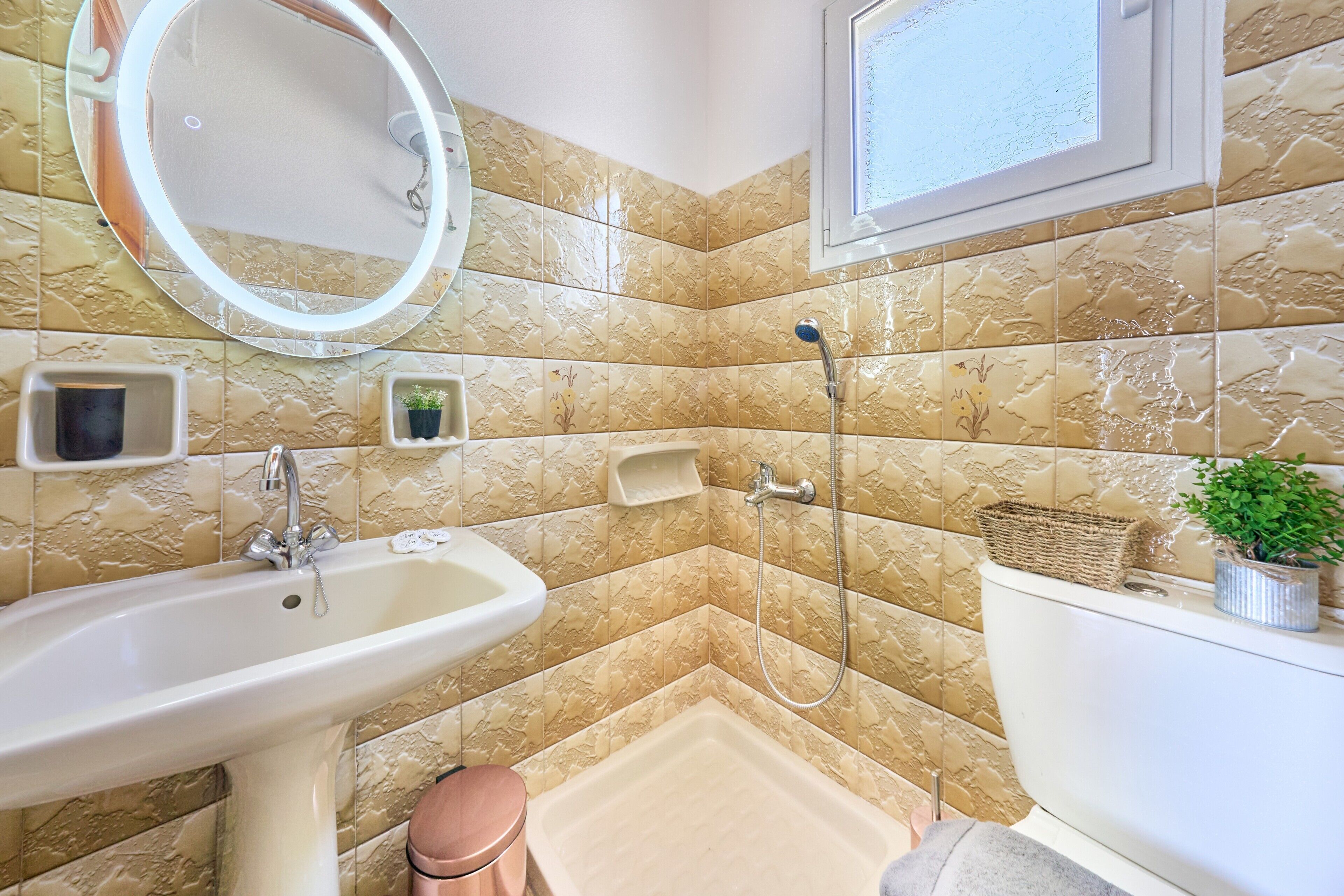 Ein Badezimmer mit Waschbecken, Spiegel, Dusche, Toilette und dekorativen Fliesen.