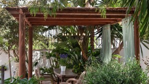 A wooden pergola with a table and chairs, surrounded by lush greenery and potted plants. - Holiday Home 'Susana' with Private Pool, Private Terrace and Wi-Fi (Santa Eulària des Riu)