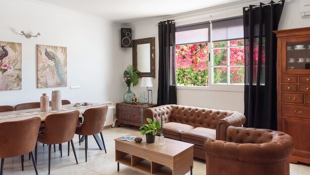 A living room with a dining table, chairs, a sofa, a coffee table, and a window with curtains. - Holiday Home 'Susana' with Private Pool, Private Terrace and Wi-Fi (Santa Eulària des Riu)
